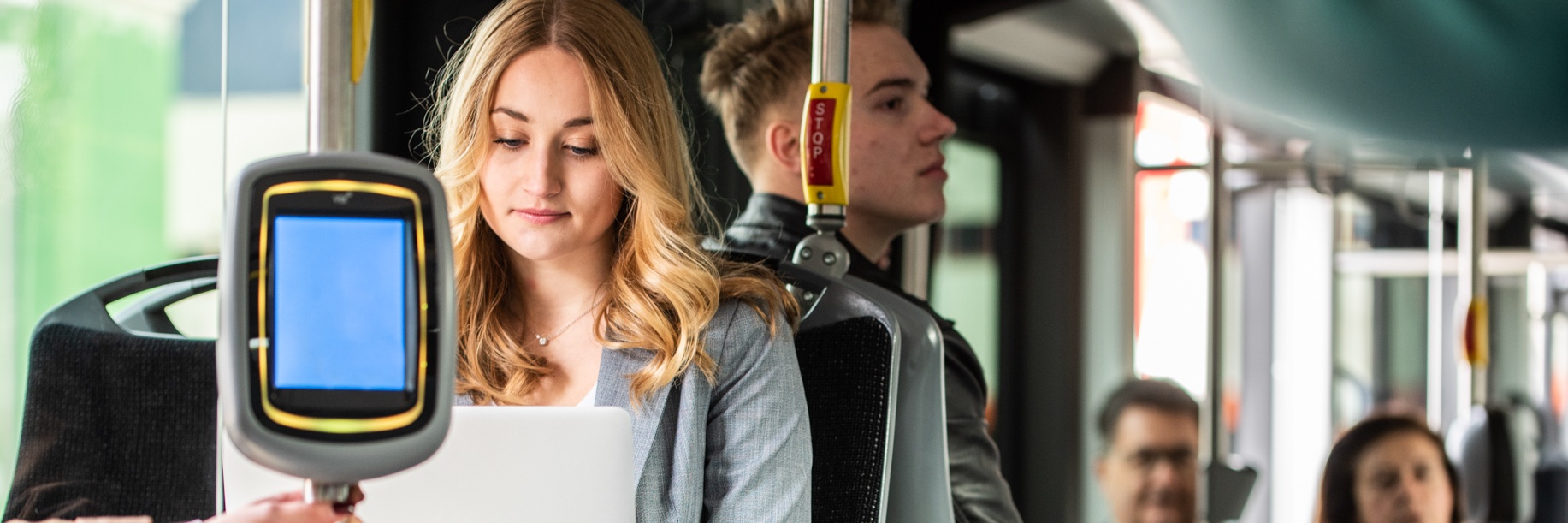 A woman is working on her laptop on the bus